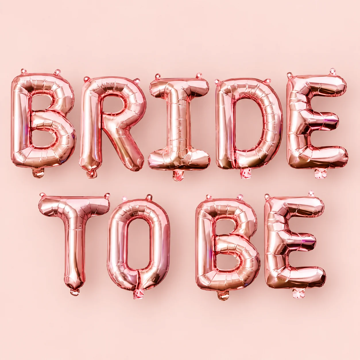 Ballons lettres BRIDE TO BE rose gold sur fond rose pâle